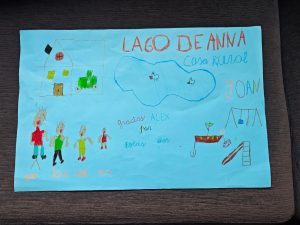 Dibujo infantil agradeciendo la estancia en la Casa Rural Lago de Anna, con elementos como una casa, el lago y una familia.