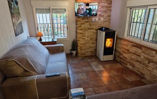Salón de La Casa del Lago en Anna, con sofá, estufa de pellets y vistas al exterior